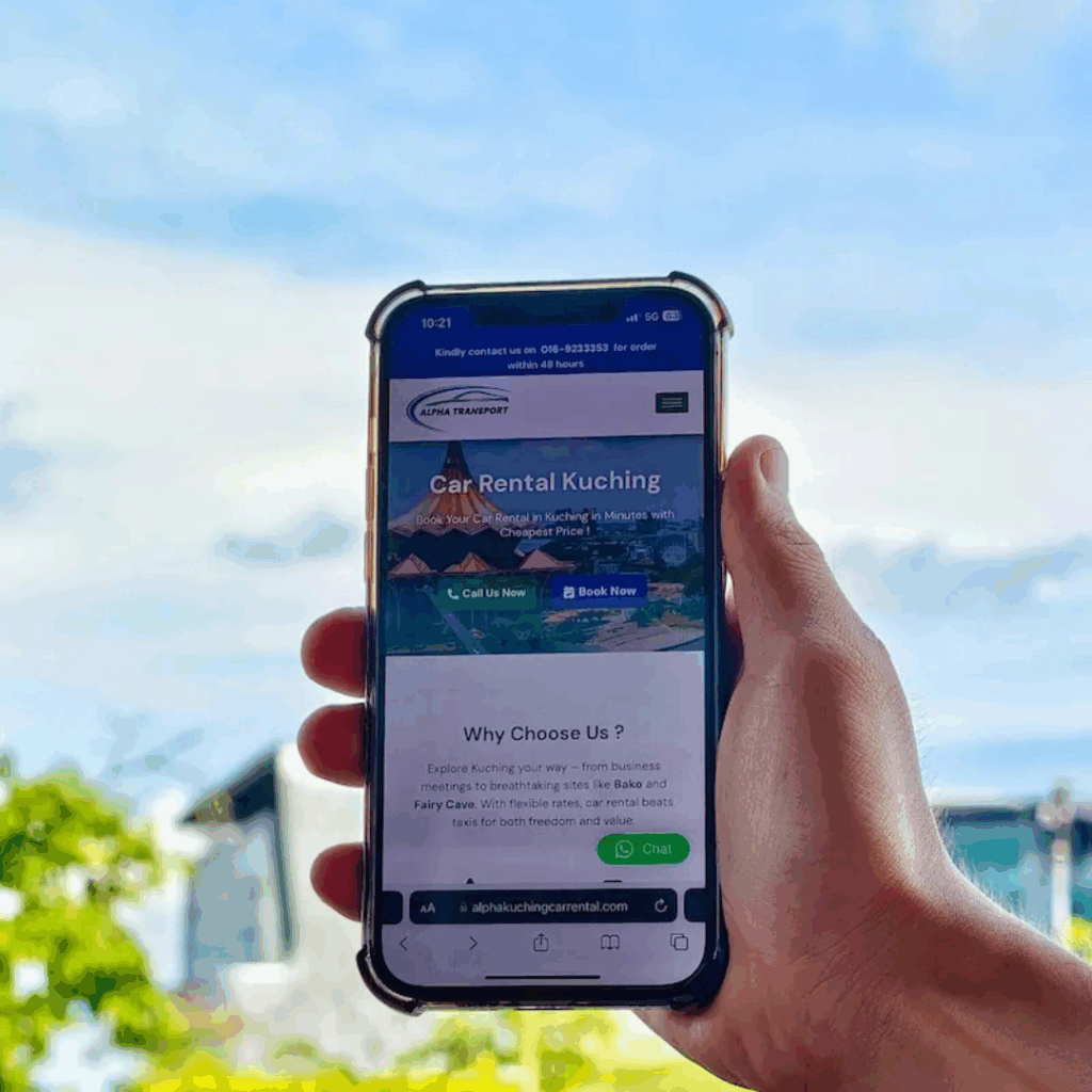 Hand holding a smartphone displaying the Alpha Transport Car Rental Kuching mobile site, featuring the "Call Us Now" and "Book Now" buttons.